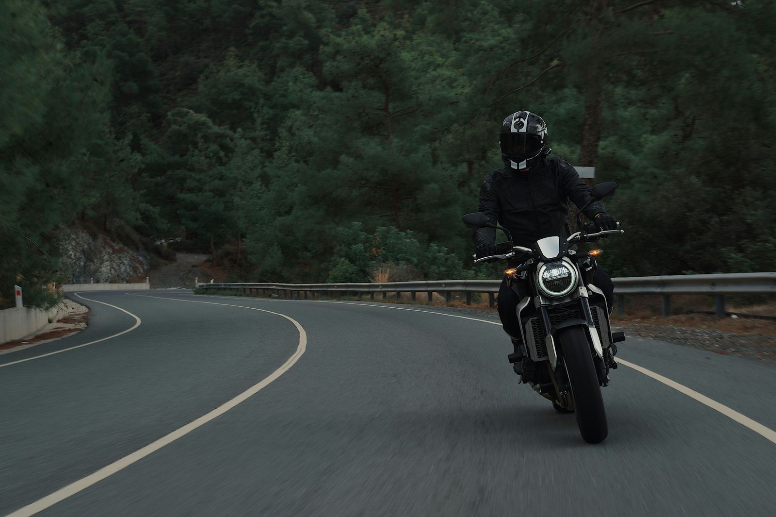 Motard sur une route sinueuse en forêt